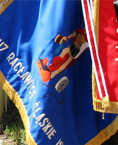 Na sztandarze również możemy zobaczyć Świętego Floriana, ale szczególną uwagę przykuwa widoczny kamień młyński, który został przywiązany do Floriana, gdy ten został wrzucony do rzeki